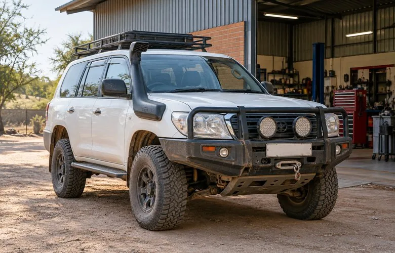 A white Land Cruiser with bull bar and snorkel outside the workshop